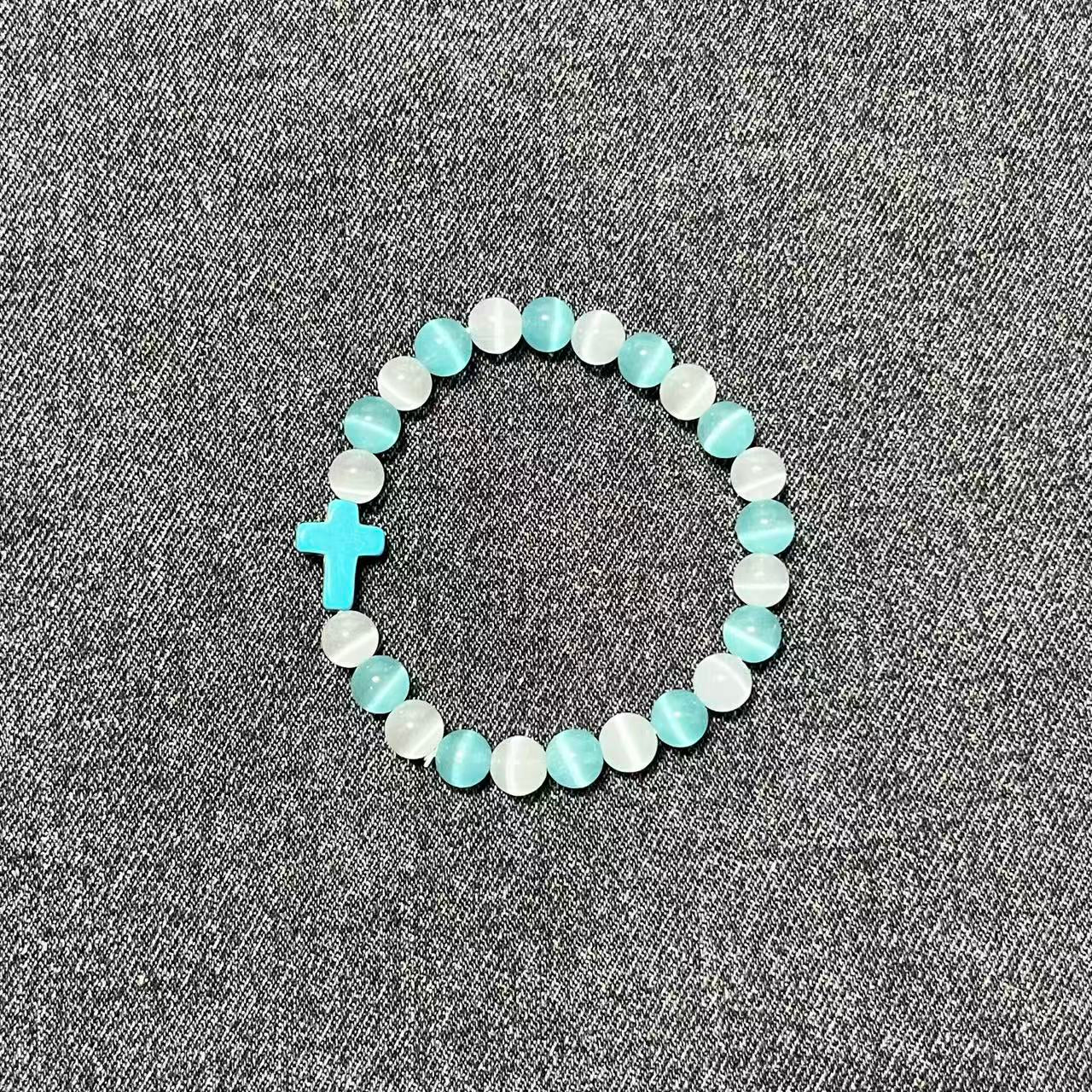 A single Aether Cross beaded bracelet made of alternating white and light blue chatoyant cat-eye crystals with a turquoise sacred cross charm.
