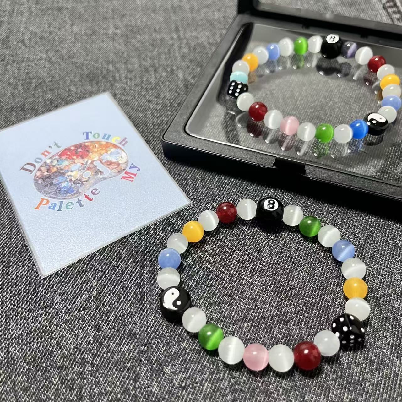 Premium black floating gift box packaging for the SpiritPalette Chroma Rebel multi-color 8-ball and dice bracelet with a signature brand collector card.